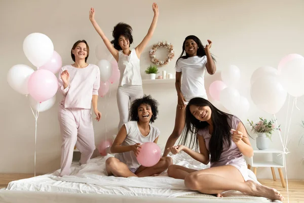 Feliz diversas chicas con ropa de dormir pasar el rato en el dormitorio del hotel — Foto de Stock