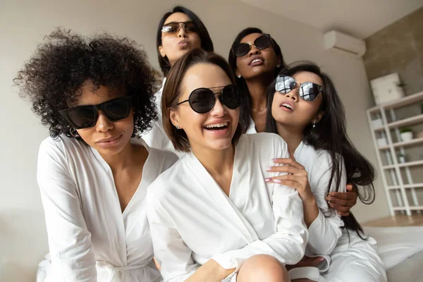Ragazze multiculturali che indossano accappatoi bianchi e occhiali da sole divertirsi al chiuso — Foto Stock