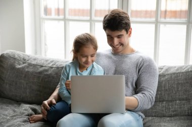Mutlu genç baba küçük kızıyla bilgisayar kullanıyor..