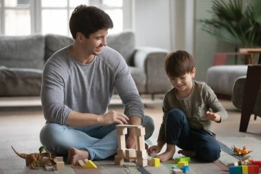 Gülümseyen genç baba, mutlu oğluyla birlikte bina inşa ediyor..