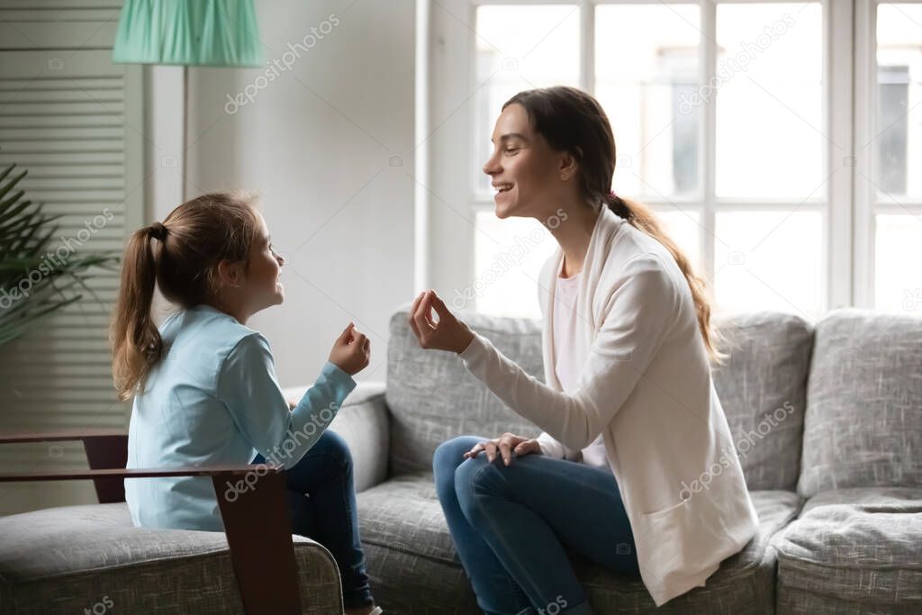 Small preschool girl involved in speaking lesson with physiotherapist.
