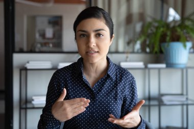 Odaklanmış genç Hintli kadın müşterilerle video görüşmesi yapıyor..
