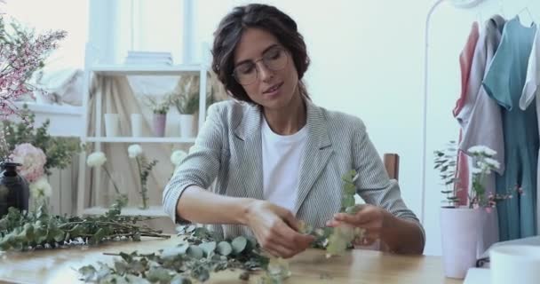 Joven diseñadora femenina arreglando ramas florales verdes en composición. — Vídeos de Stock