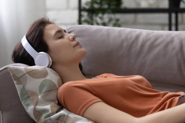 Kulaklıklı kız evde müzik dinliyor.