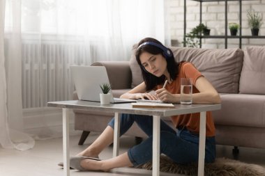 Kulaklıklı Milenyum kızı evde online ders alıyor.