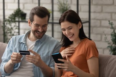 Gülümseyen çift kartla cep telefonundan alışveriş yapıyor.
