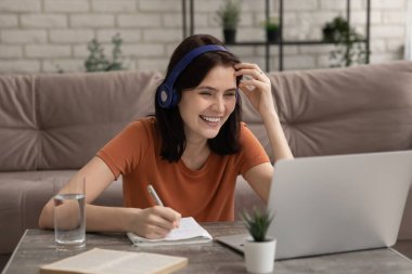 Gülümseyen kız dizüstü bilgisayarı izle ve not al.