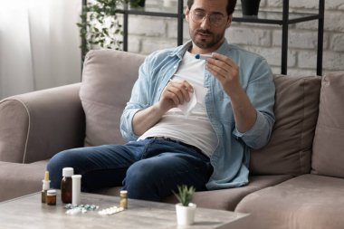 Sağlıksız bir adam evde kendini hasta hissederken ölçer.