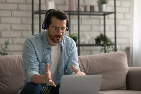 Caucasian man in headphones talk on video call on laptop — Stock Photo, Image