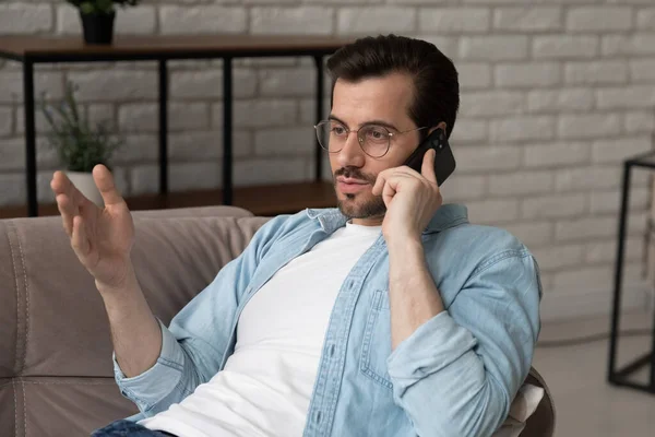 Young man in glasses talk on smartphone at home — Stock Photo, Image