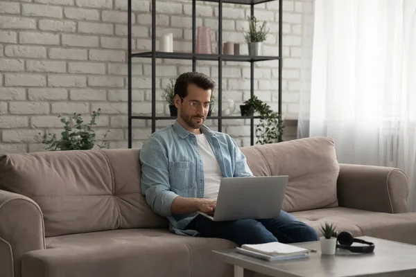 Kaukasische man zitten op de bank werken op laptop thuis — Stockfoto