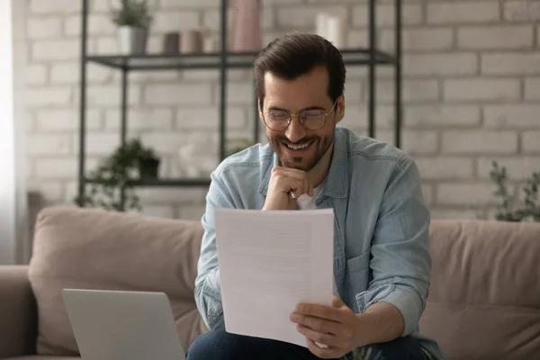 Glimlachende man voelt zich opgewonden bij het lezen van goed nieuws in papieren brief — Stockfoto