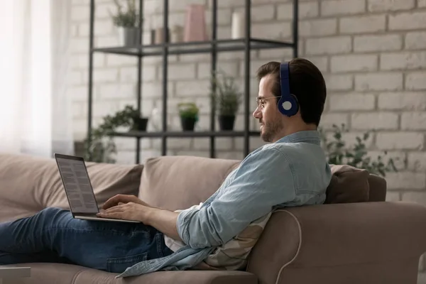 Caucasian man in headphones work on laptop at home