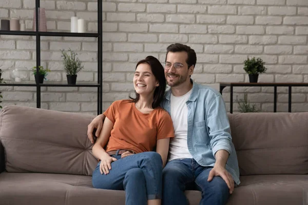 Feliz joven pareja relajarse en el sofá en casa soñando — Foto de Stock