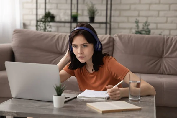 Menina focada em fones de ouvido estudo no laptop em casa — Fotografia de Stock