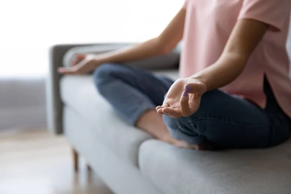 Cultivo de mujer sentada en sofá practicando yoga — Foto de Stock