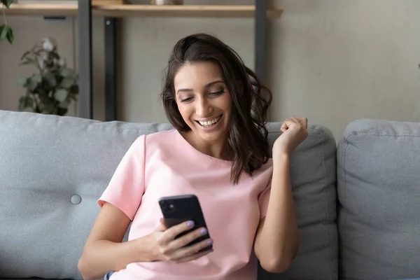 Mulher étnica excitada recebe mensagem agradável no celular — Fotografia de Stock