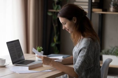 Gülümseyen genç kadın kağıt mektupları okuyor.