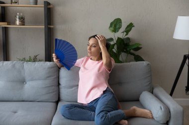 Kötü niyetli etnik kadın evde el yelpazesiyle el sallıyor