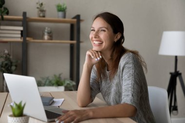 Gülümseyen genç kadın laptopta gülüyor ve konuşuyor.