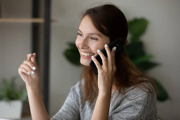 Smiling young woman talk on smartphone gadget