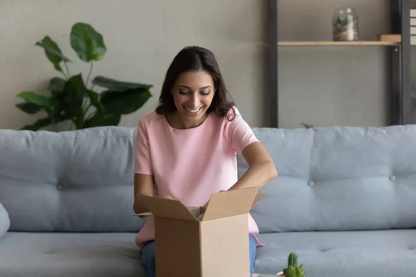 Mujer étnica feliz desempaquetar paquete de entrega postal en casa —  Fotos de Stock