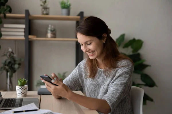 Sorridente donna caucasica divertirsi a messaggiare su smartphone — Foto Stock