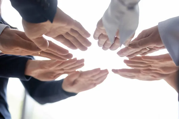Compañeros de equipo de pie en círculo extendiendo las manos hacia adelante con las palmas hacia abajo —  Fotos de Stock