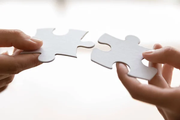 Hands of two people connecting pieces of puzzle — Stock Photo, Image