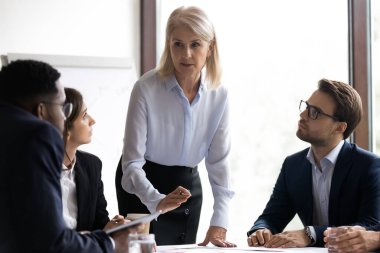 Olgun kadın eğitmen çeşitli şirket çalışanlarına ders veriyor.