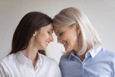 Anne ve yetişkin kız yüz yüze durup birbirlerine dokunuyorlar.