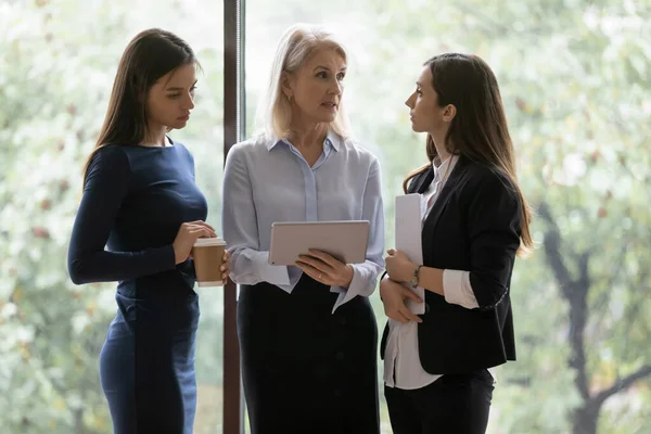 Jeunes femmes employées demandant conseil à une collègue expérimentée — Photo