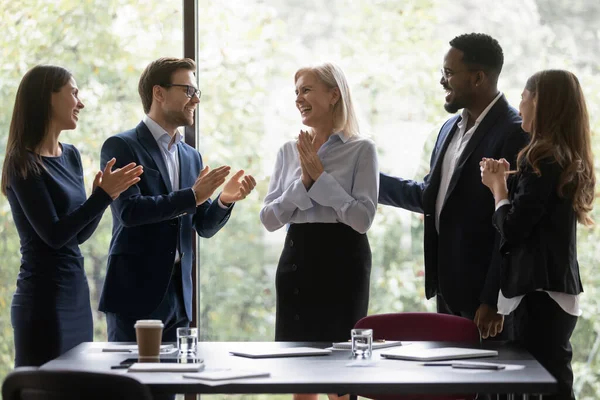 Gelukkige ondergeschikten feliciteren volwassen vrouwelijke baas met persoonlijke prestatie — Stockfoto