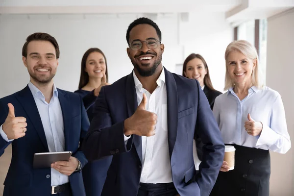 Gelukkige Afrikaanse baas en zijn gevarieerde team tonen duimen omhoog — Stockfoto