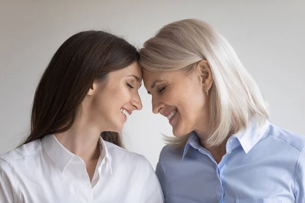 Mother and grown daughter standing face to face touching heads — Stock Photo, Image