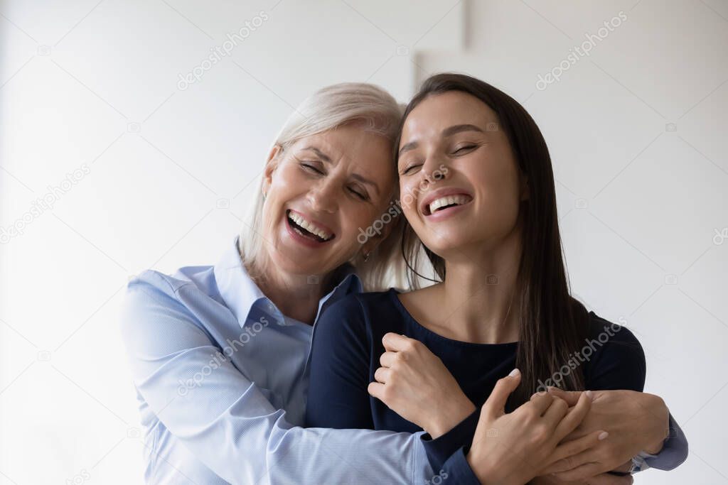 Excited mature mother and adult daughter laughing happily