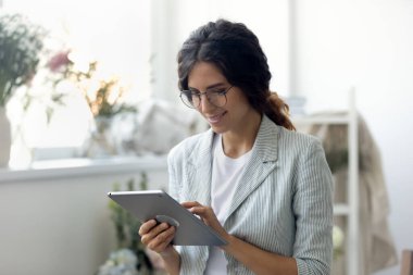 Gülümseyen genç ve güzel iş kadını bilgisayar tabletinde internet sörfü bilgisi.