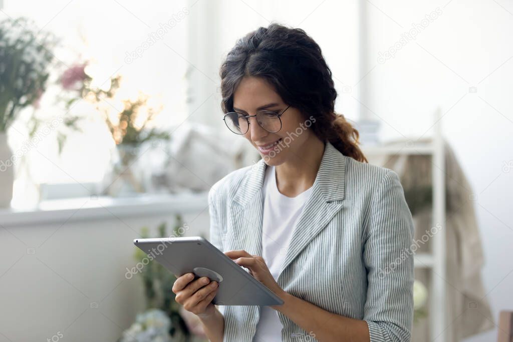 Smiling young beautiful businesswoman web surfing information in computer tablet.