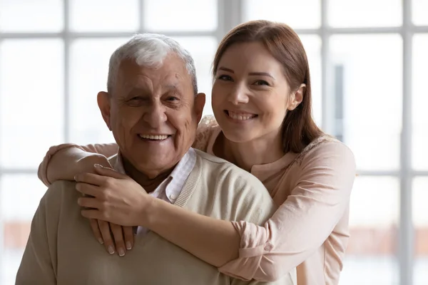 Hoofd schot portret van glimlachende jonge vrouw knuffelen oude vader. — Stockfoto