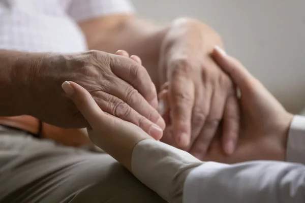 Medische werker houdt hand in hand van oude 70-er jaren gepensioneerde patiënt. — Stockfoto
