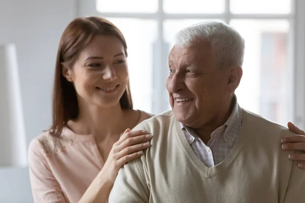 Mujer joven abrazando hombros de jubiloso anciano maduro 70 padre. — Foto de Stock