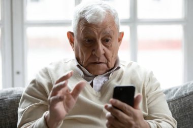 70 'lerin emekli ihtiyarı akıllı telefon ekranına bakıyor..