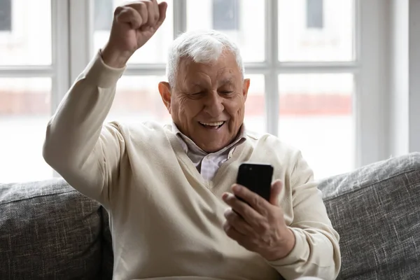 Emocionado anciano maduro jubilado hombre celebrando la lotería en línea ganar. — Foto de Stock