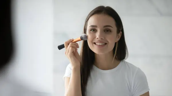 Fechar a cabeça tiro sorrindo mulher aplicando blush nas bochechas — Fotografia de Stock