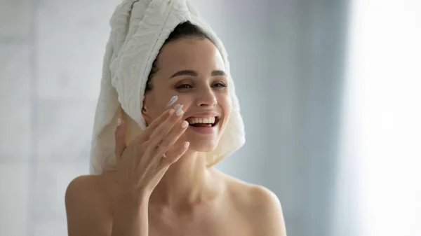 Gros plan jeune femme souriante appliquant crème hydratante après la douche — Photo