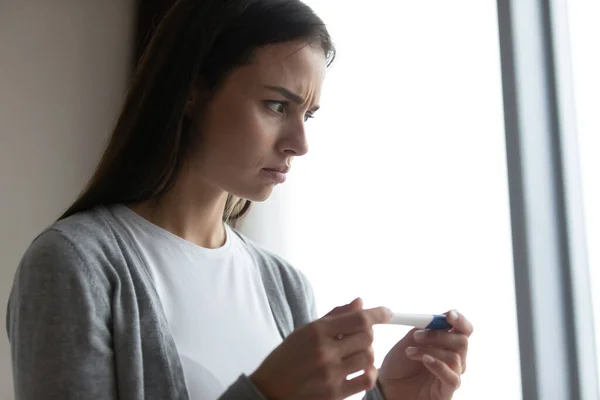 Close up anxious unhappy young woman holding plastic pregnancy test — Stock Photo, Image