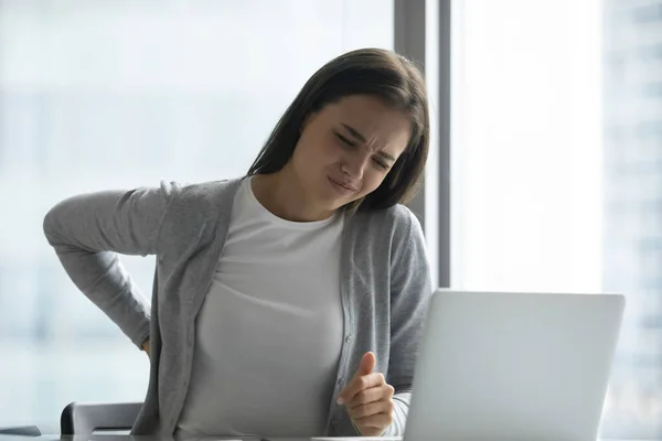 Estressado cansado jovem empresária sofrendo de dor nas costas no escritório — Fotografia de Stock