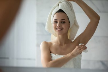 Yakın çekim. Gülümseyen kadın duştan sonra deodorant sürüyor.