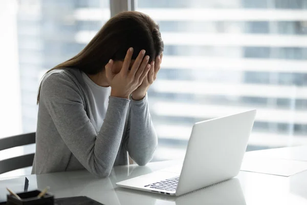 Femme d'affaires frustrée surmenée couvrant le visage avec les mains, assise au bureau — Photo