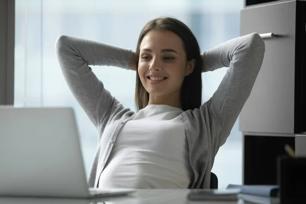 Smiling satisfied young businesswoman looking at laptop screen, relaxing — Stock Photo, Image